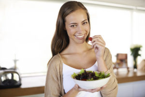 A cropped portrait of a beautiful young woman eating a bowl of salad in her kitchen